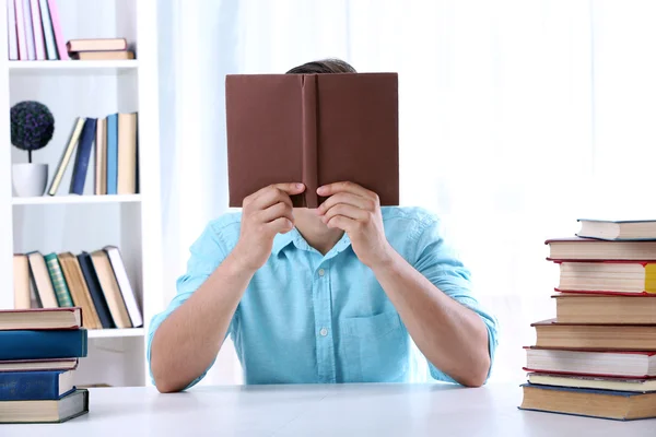 Joven leyendo libro en la mesa en la habitación — Foto de Stock