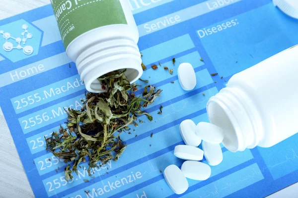 Бутылки сухой медицинской марихуаны и таблетки на столе крупным планом — стоковое фото