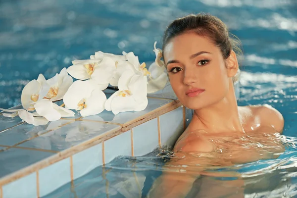 수영장에서 꽃과 아름 다운 젊은 여 인 — 스톡 사진