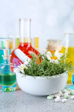 Harç, test tüpleri ve hapları, masada açık renkli otlar