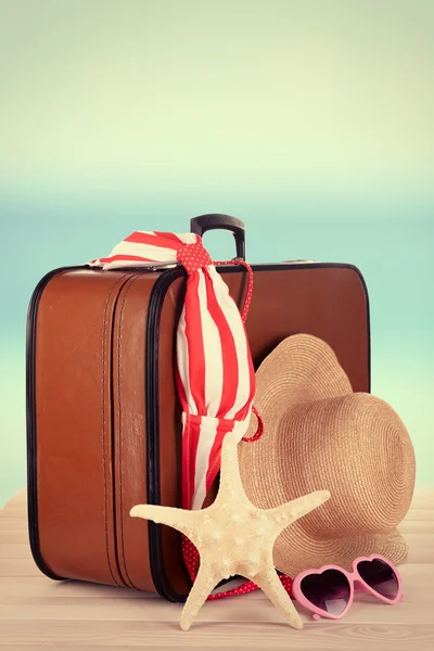 Maleta y accesorios para viajar sobre fondo de playa —  Fotos de Stock