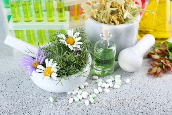 Herbs in mortar, test tubes and pills,  on table, on light background — Stock Photo, Image