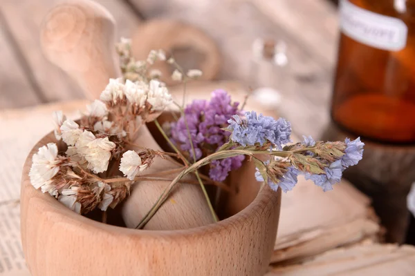 Oud boek met droge bloemen in mortel en flessen op tafel close-up — Stockfoto