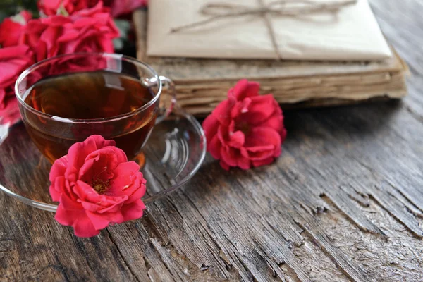 Vieux livre avec de belles fleurs et une tasse de thé sur une table en bois close up — Photo