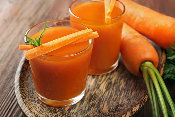 Se acercan los vasos del jugo de zanahoria con hortalizas a la mesa —  Fotos de Stock