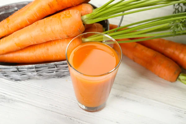 Стакан морковного сока с овощами на деревянном столе — стоковое фото
