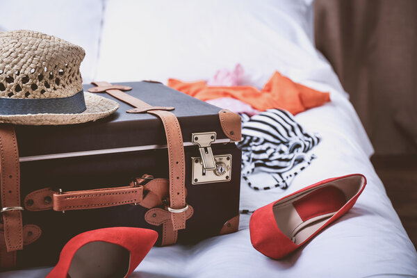 Чемодан с одеждой на кровати в номере
