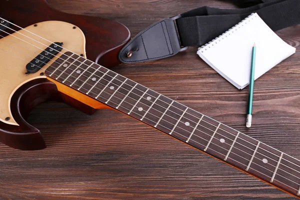 Chitarra elettrica con notebook su tavolo di legno da vicino — Foto Stock