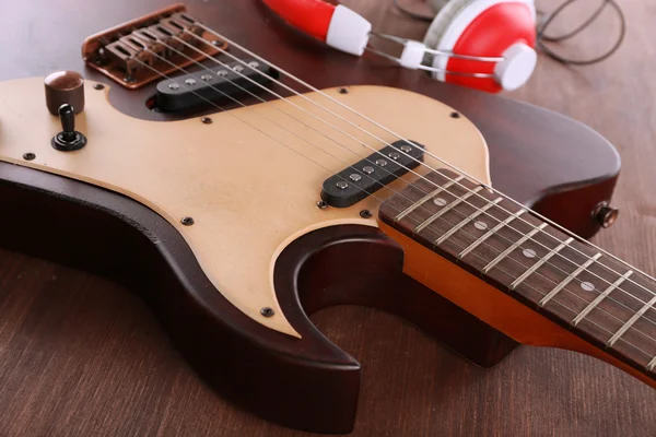 Elektrická kytara se sluchátky na dřevěný stůl zblízka — Stock fotografie