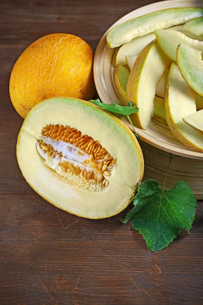 Melons mûrs aux feuilles vertes sur table en bois close up — Photo