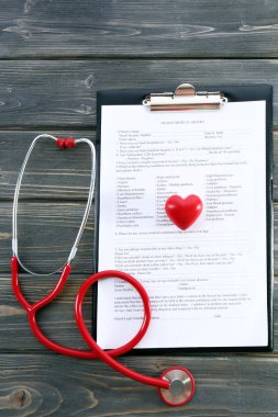 plastik kalp ve tıbbi geçmişi ahşap arka plan üzerinde kırmızı lastik stetoskop
