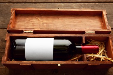 Ahşap arka plan üzerinde saman ile zarif durumda pahalı şarap