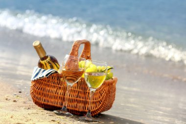 Piknik sepeti şişe şarapla kum plaj