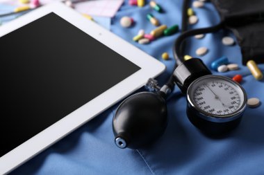 Tansiyon ölçer, stetoskop, koyu arka plan üzerinde dijital tablet