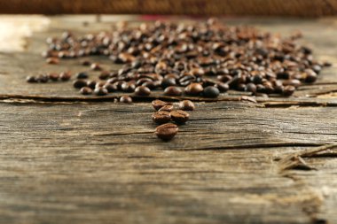 Ahşap arka planda kavrulmuş kahve çekirdekleri.