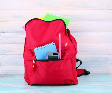 Okul malzemeleri ahşap arka plan üzerinde kırmızı çanta