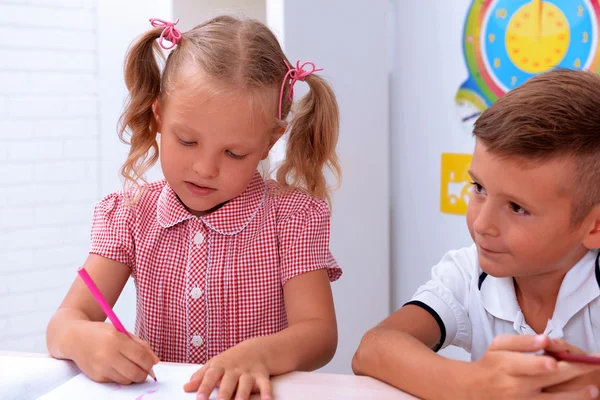 Niña dibujando en el escritorio en el aula — Foto de Stock