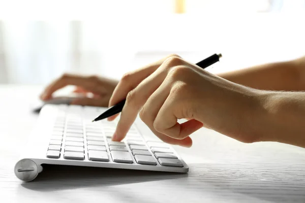 Female hand with pen typing on keyboard at table, closeup — Stock Photo, Image