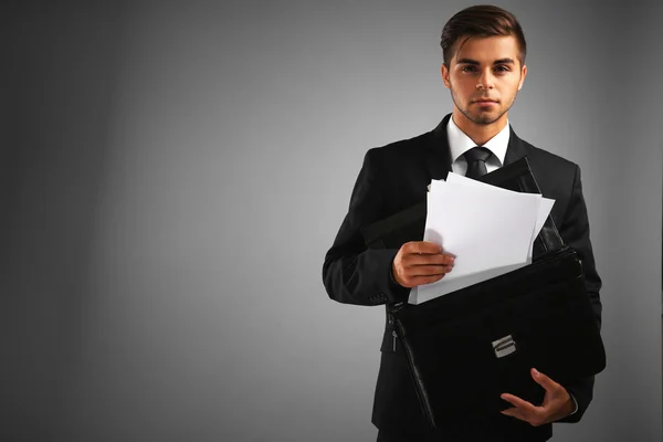 Elegant man in suit with briefcase on gray background — Stock Photo, Image