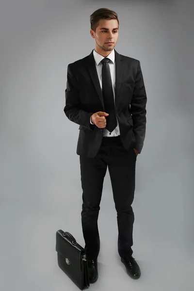 Homem elegante em terno com pasta em fundo cinza — Fotografia de Stock