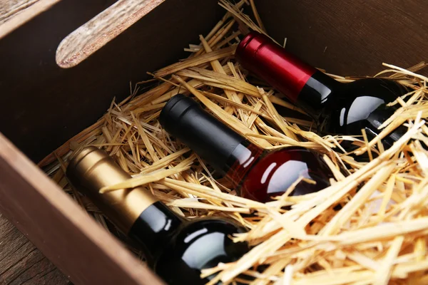 Tres botellas de vino en caja con paja — Foto de Stock