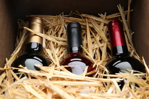 Three wine bottles in box with straw — Stock Photo, Image