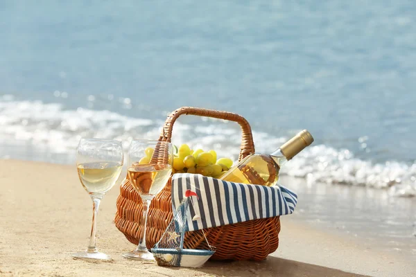 砂のビーチでワインのボトル付きピクニック バスケット — ストック写真