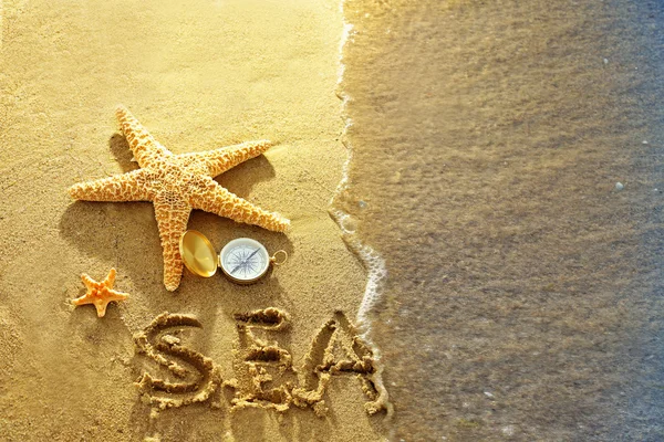 Kompas met zeesterren op zand strand achtergrond — Stockfoto
