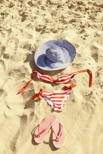Chinelos, maiô e chapéu na praia closeup areia — Fotografia de Stock