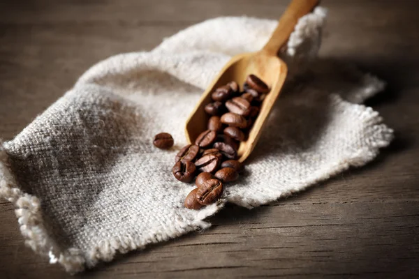Grãos de café sobre tecido branco e fundo de madeira — Fotografia de Stock
