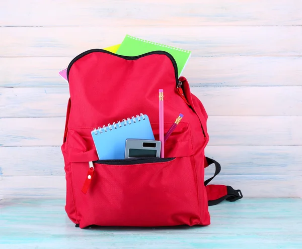 Bolso rojo con equipo escolar sobre fondo de madera — Foto de Stock