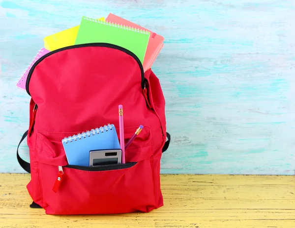 Saco vermelho com equipamento escolar em fundo de madeira — Fotografia de Stock