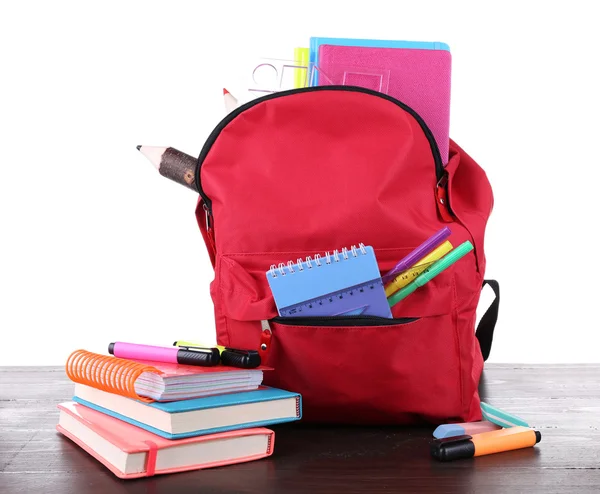 Borsa rossa con attrezzatura scolastica su tavolo di legno isolato su bianco — Foto Stock