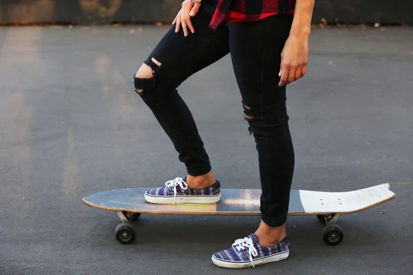 Mujer joven con tabla de patinar en la carretera —  Fotos de Stock