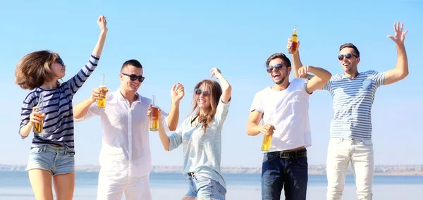 Young people with beer on the riverside — Stock Photo, Image