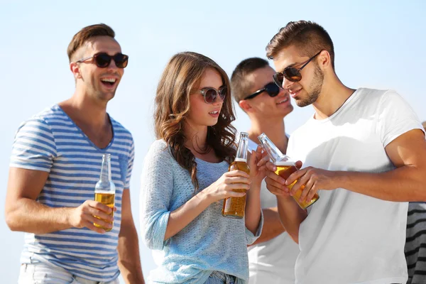 Молодые люди с пивом на берегу реки — стоковое фото