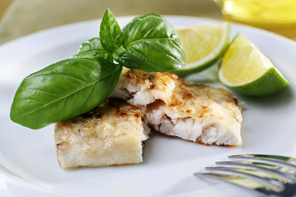 Maträtt av fiskfilé med basilika och lime på plattan på nära håll — Stockfoto