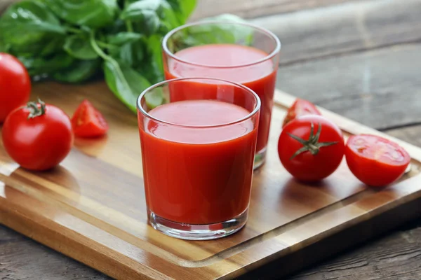 Szklanki soku pomidorowego na drewnianym stole, zbliżenie — Zdjęcie stockowe