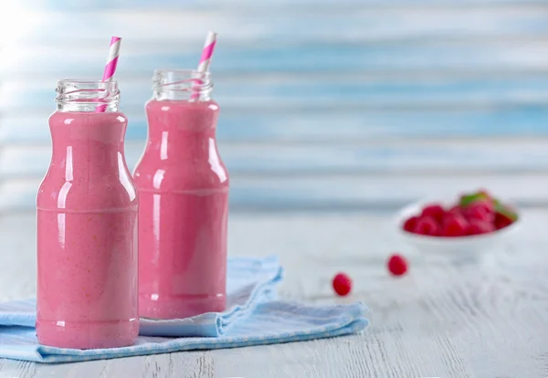 Bottles of raspberry milk shake with berries on wooden table close up — Stock Photo, Image