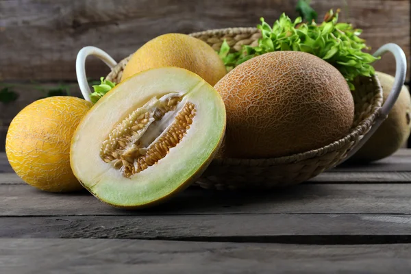 Rijpe meloenen met groene bladeren in mand — Stockfoto