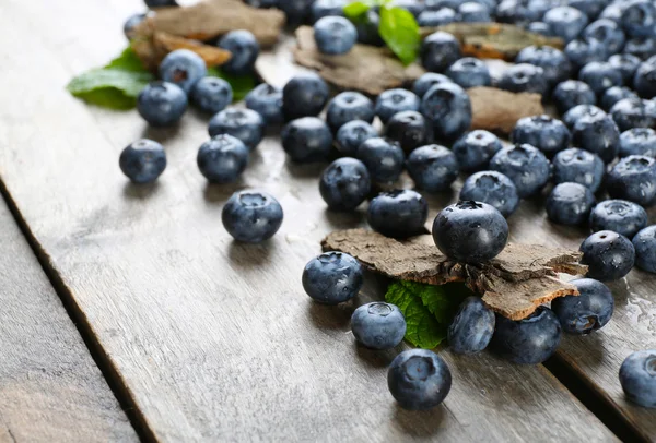 Leckere reife Blaubeeren mit grünen Blättern — Stockfoto