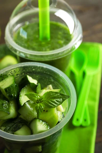 Green vegetable and fruit salad and healthy fresh drink in plastic cups on wooden background. Colorful diet concept — Stock Photo, Image