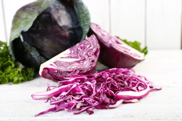 Cut red cabbage and parsley on wooden table — Stock Photo, Image