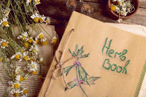 Altes Buch mit trockenen Blumen im Mörser auf dem Tisch in Großaufnahme — Stockfoto