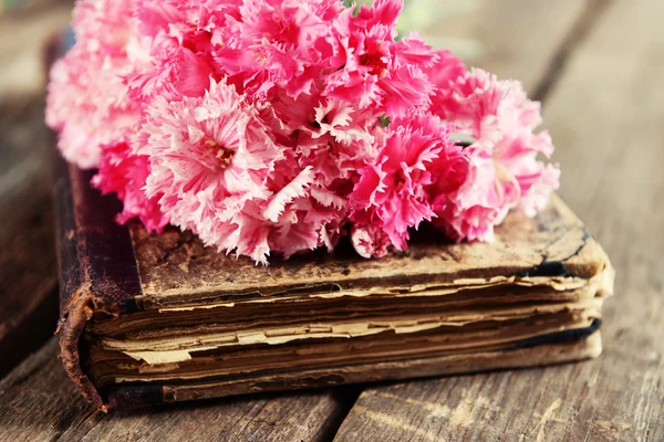 Gammal bok med vackra blommor på träbord nära håll — Stockfoto