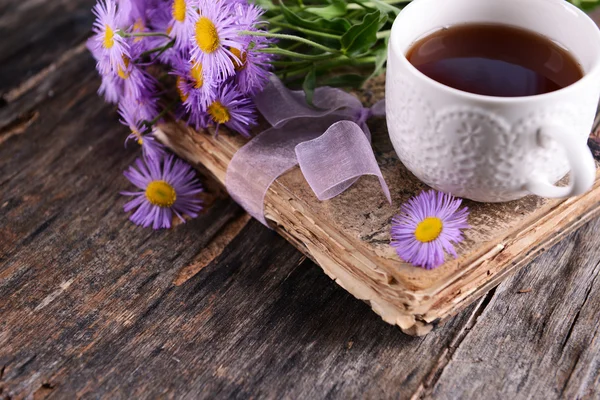 Vecchio libro con bellissimi fiori e tazza di tè sul tavolo di legno da vicino — Foto Stock