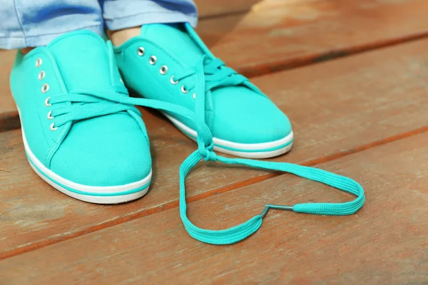 Pés femininos em sapatos de goma no fundo do chão de madeira — Fotografia de Stock