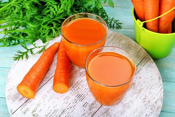 Bicchieri di succo di carota con verdure su sfondo di legno — Foto Stock