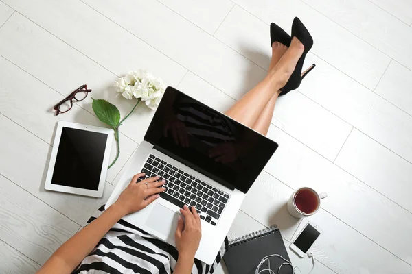 Jonge vrouw zitten op de vloer met laptop — Stockfoto