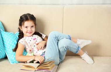 Küçük kız kanepede kitap ile yalan